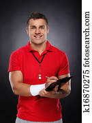 Young Coach. Portrait of cheerful young coach holding a clipboard and whistle.