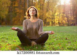 Beautiful young girl meditating in autumn park