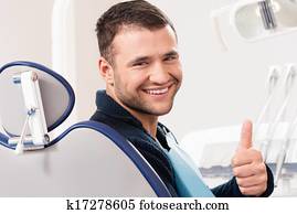 Smiling young man at dentist's surgery with thumb up Smiling young man at dentist's surgery with thumb up