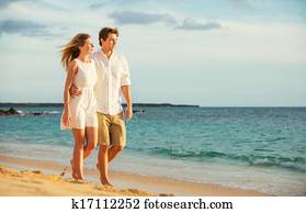 Young couple in love walking on the beach at sunset