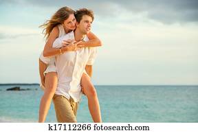 Young couple in love walking on the beach at sunset