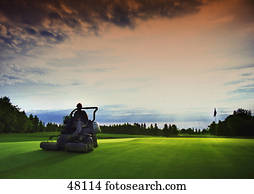 Greens keeper on mower cutting grass Greens keeper on mower cutting grass