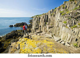 Hiker along basalt rock cliffs, Bay of Fundy; Brier Island, Nova Scotia, Canada