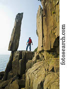 Hiker viewing the Balancing Rock and basalt rock cliffs, Bay of Fundy; Long Island, Nova Scotia, Canada