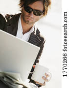 Man working on computer holding coffee