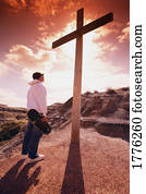 Skateboarder standing before a cross