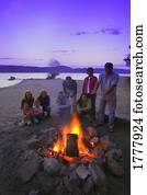 A group of people around a fire on the beach A group of people around a fire on the beach