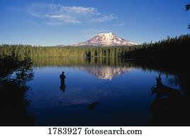 Fisherman in Takhlakh Lake with reflection of distant Mount Adams.