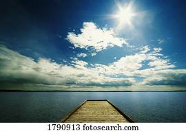 Bright sun over dock on lake