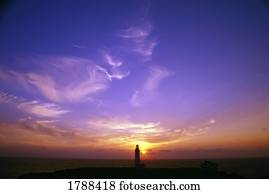 Luminous sky behind distant lighthouse