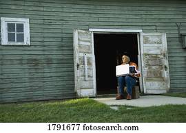 Man working on computer outside of barn or shed