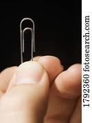 Person holding up a paperclip