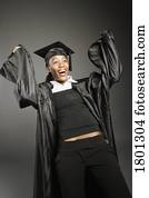 Young woman rejoicing in graduation cap and gown