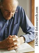 Elderly man praying with the Bible Elderly man praying with the Bible