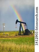 Storm clouds and rainbow over prairie oil pump  