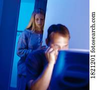 Man working at computer with sad woman in background