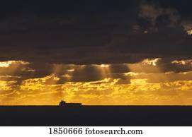 Cargo Ship, Atlantic Ocean; Ship silhouetted in the distance in the ocean