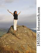 Woman on mountain peak with arms raised