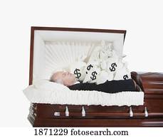 a deceased man in a coffin surrounded by bags of money