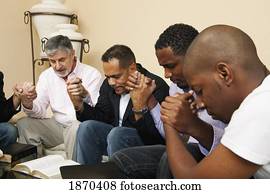 a group of men praying together with an open bible