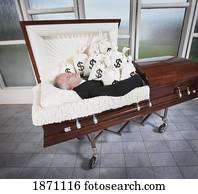 a man laying in a coffin surrounded by bags of money