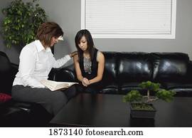 a woman praying for a young woman with an open bible a woman praying for a young woman with an open bible