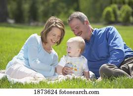 parents sitting on the grass with their young son