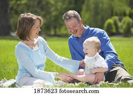 parents sitting on the grass with their young son