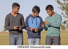brothers texting and walking through a park; edmonton, alberta, canada