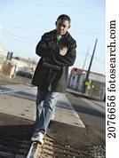 Teenage boy holding a school book and walking on train tracks; portland oregon united states of america
