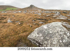 Rock on a rugged landscape under a cloudy sky; ireland