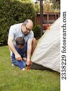 A father and son pitch a tent in the backyard; Pacifica, California, United States of America