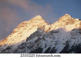 neve, peaked, montanha, com, brilho alaranjado, de, amanhecer, com, céu azul, e, nebuloso, clouds;, kananaskis, país, alberta, canadá