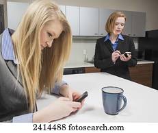 Co-workers texting during a coffee break; Edmonton, Alberta, Canada