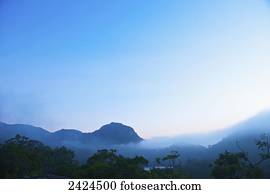Mountains with low cloud against a blue sky at sunrise; Ulpotha, Embogama, Sri Lanka