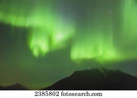 Northern Lights in the sky above Moose Pass, with silhouetted Kenai Mountains in the fog and low cloud, Chugach National Forest; Moose Pass, Alaska, United States of America