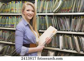 Young woman filing documents at an accounting office; Edmonton, Alberta, Canada
