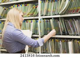 Young woman filing documents at an accounting office; Edmonton, Alberta, Canada