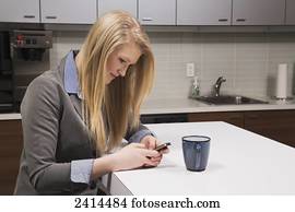 Young woman texting on her break in the lunch room at the office; Edmonton, Alberta, Canada