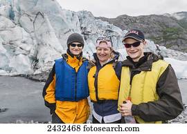 Mother with two teenage sons wearing life jackets, standing in front of Shoup glacier and Chugach mountains, Shoup Bay State Marine Park, Prince William Sound; Valdez, Alaska, United States of America