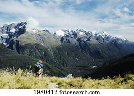 Hiker viewing mountains from Routeburn Track in Fiordlands National Park; New Zealand