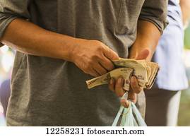 Man counting money in his hand with shopping bag at Old Market; Battambang, Cambodia
