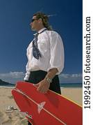 Man Standing On Beach In Business Suit Holding A Surfboard.