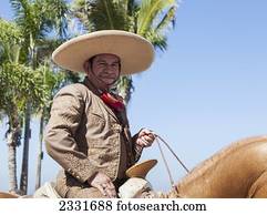 Mexico, specific type of Mexican rodeo here in parade; Puerto Vallarta, The traditional Mexican charro is known for colorful clothing and participating in coleadero y charreada