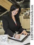 Professional businesswoman making notes on office interior construction project; Edmonton, Alberta, Canada