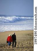 Senior Couple Walking On Beach View From Behind, Arm In Arm, White Shorebreak