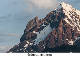 Snow-capped rugged mountain peak with blue sky and cloud