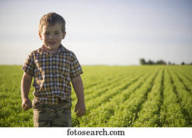 Young boy standing in a farm field in summertime; Saskatchewan, Canada