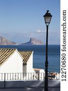 Lamppost and buildings along the coast with a rugged coastline in the distance; Altea, Spain