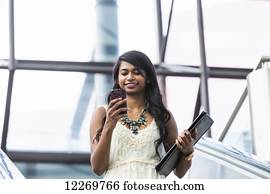 Young professional businesswoman texting on her smart phone on escalator; Edmonton, Alberta, Canada Young professional businesswoman texting on her smart phone on escalator; Edmonton, Alberta, Canada